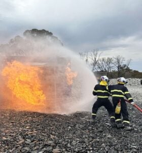 firefighting equipment - 2 firefighters using a fire hose and nozzle to fight a fire