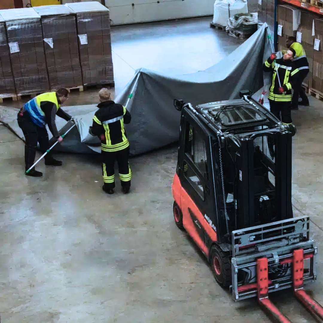 people prrepping telescopic poles and lithium-ion fire blanket to cover forklift