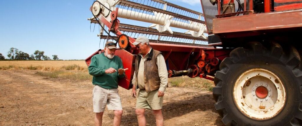 farmers standing by a harvester in a field